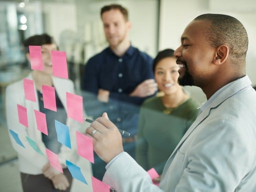 Man in office showing sticky notes to his coworkers.